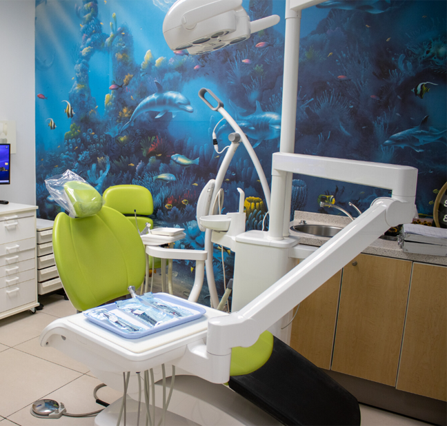 pediatric dental operatory featuring bright green examination chair against an underwater ocean mural background